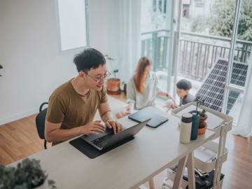 Ein Mann im Home Office mit Frau, Kind und Balkonkraftwerk im Hintergrund. © Erdark / E+ via Getty Images (ID: 1358699690)