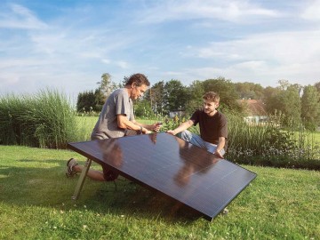 Zwei Männer stellen ein Balkonkraftwerk im Garten auf. © solago