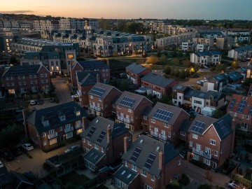 Luftaufnahme einer modernen, solarbetriebenen Wohnsiedlung in der Abenddämmerung. © Richard Newstead / Moment via Getty Images.