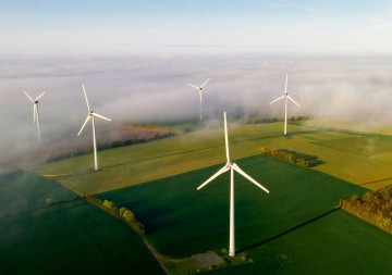 Luftaufnahme von Windkraftanlagen an einem nebligen Morgen. © Justin Paget / DigitalVision via Getty Images