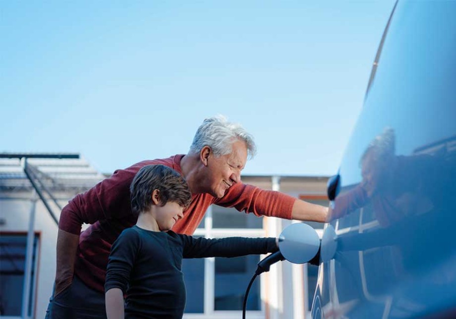 Großvater und Enkelkind laden E-Auto zuhause. © Westend61 / Westend61 via Getty Images