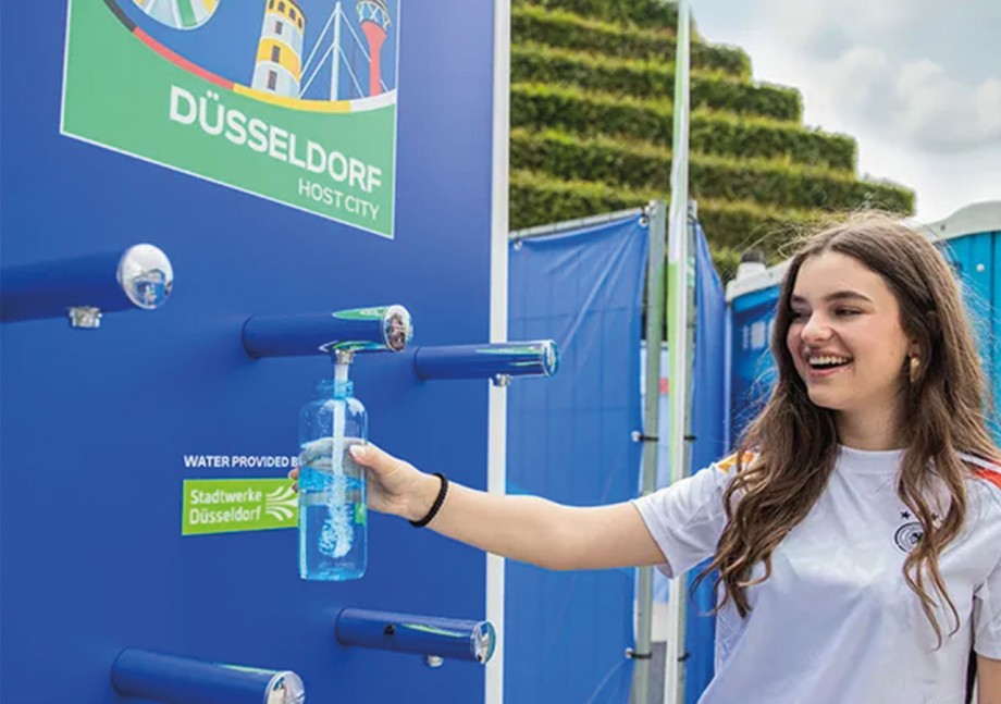 Eine junge Frau füllt ihre Trinkflasche an einem Trinkwasserspender der Stadtwerke Düsseldorf auf